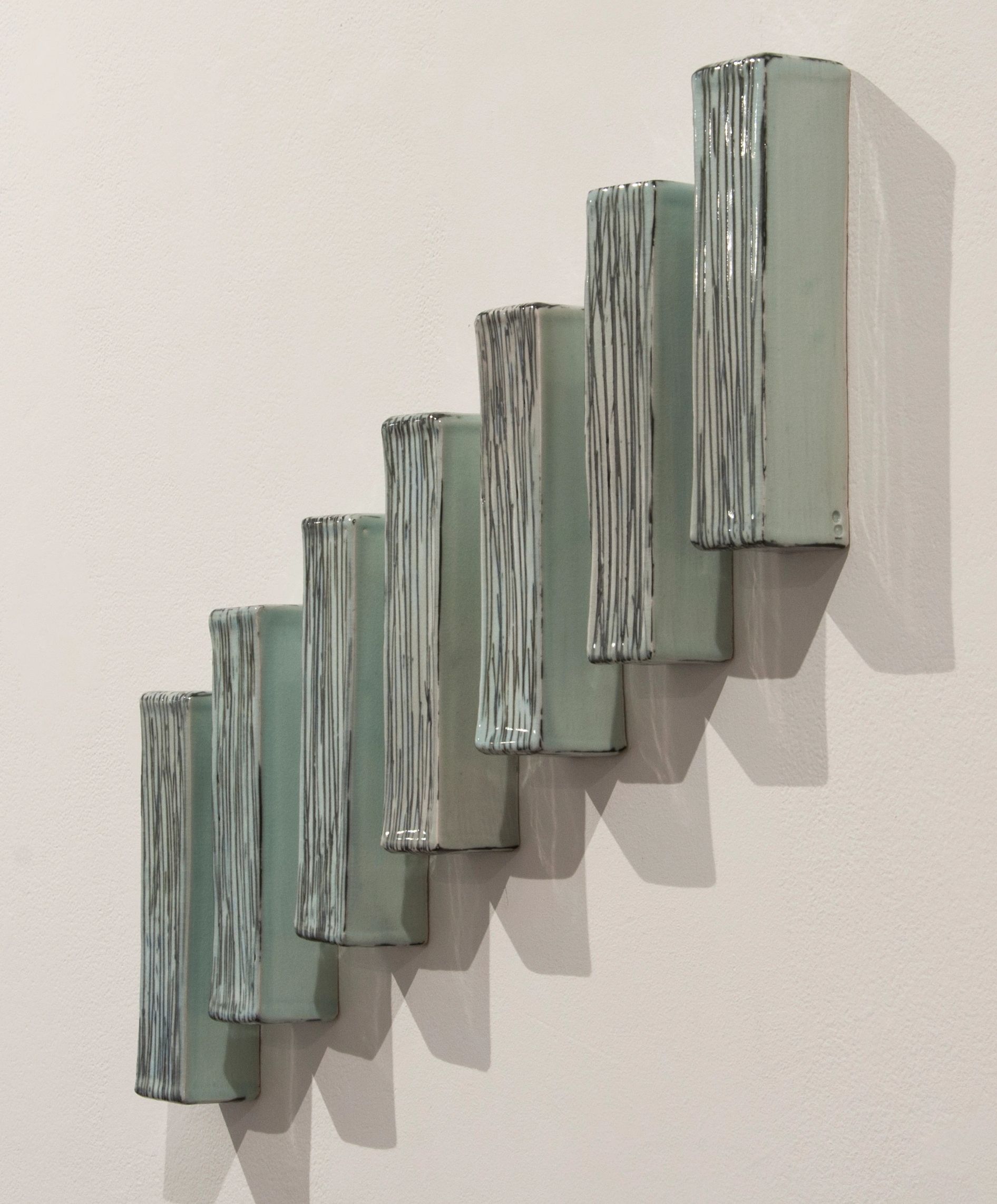 Seven porcelain rectangular forms installed on the wall using the shadows as part of the composition