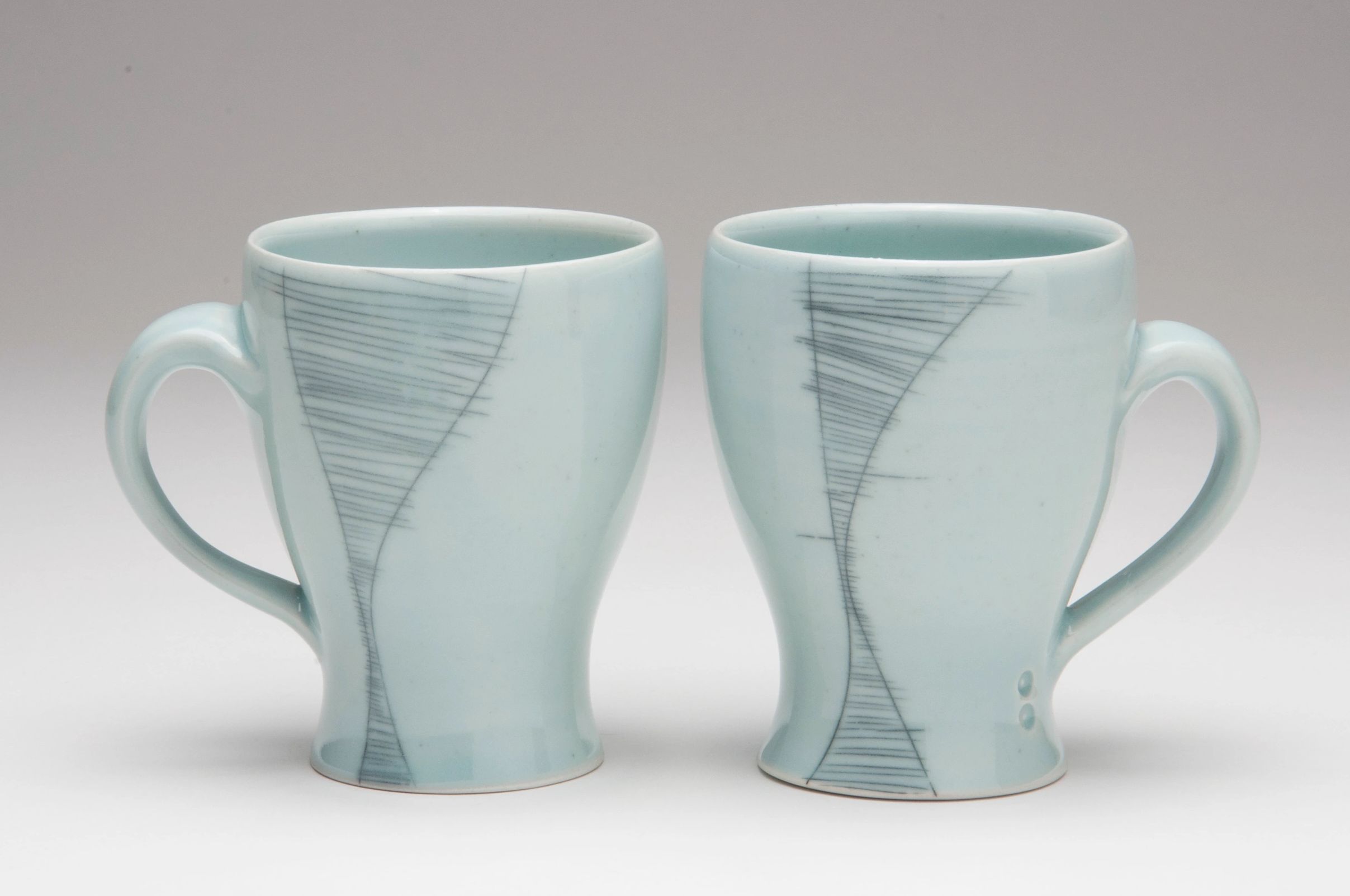 Two porcelain mugs glazed with a celadon glaze