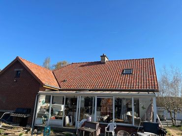 Achterzijde met nieuw dak in rood Latem, harmonieus met veranda en tuin.