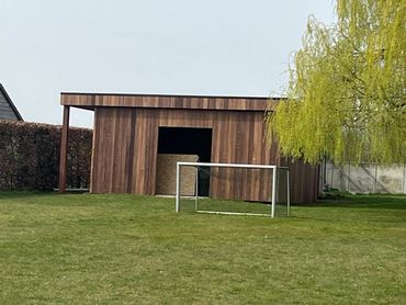 Nieuw tuinhuis met padouk planchetten en strakke afwerking, naadloos in de tuin
