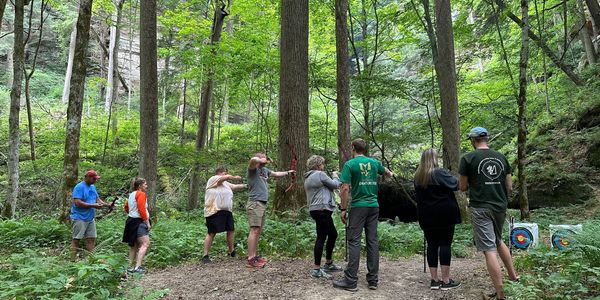 Group shooting archery in the woods