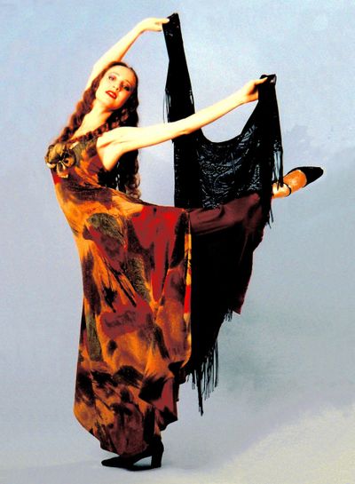A graceful dancer in a flowing dress poses with a black shawl.