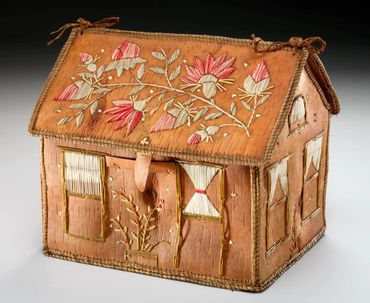 A handcrafted decorative house with floral embroidery on roof and walls.