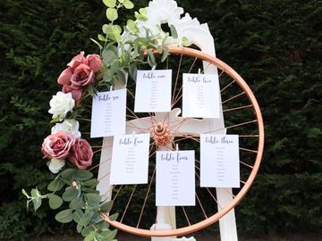 a stylish bike wheel in rose gold, mounted on a vintage easel, for table seating plans. for hire
