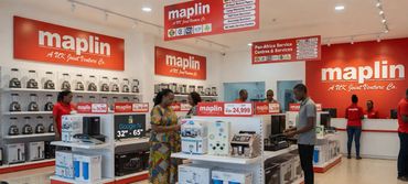 Electronics store interior with customers browsing products and staff assisting.