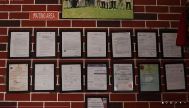 Wall display of framed certificates and documents in a waiting area.