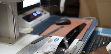 A close-up of a sewing machine working on a black leather strap.