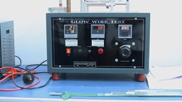 Glow wire test machine with digital displays and controls on a blue table.