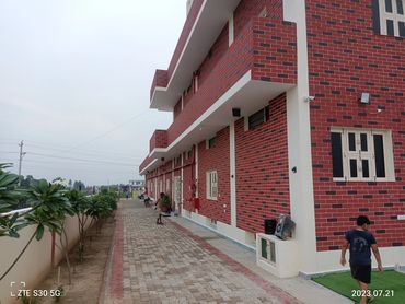 Modern red brick building with a paved walkway and plants along the side.