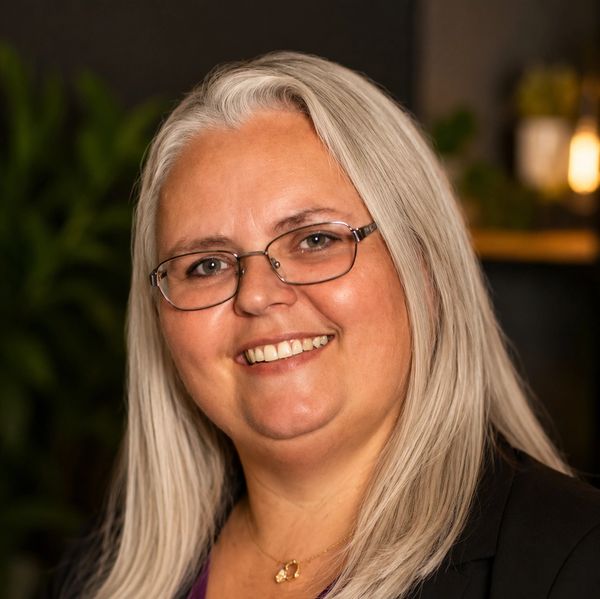 Smiling woman with glasses and long gray hair.