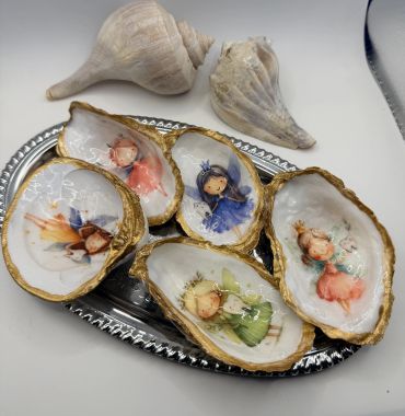 Decorative shells painted with whimsical fairy illustrations on a silver tray.