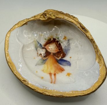 Decorative shell dish with a fairy illustration and gold trim.