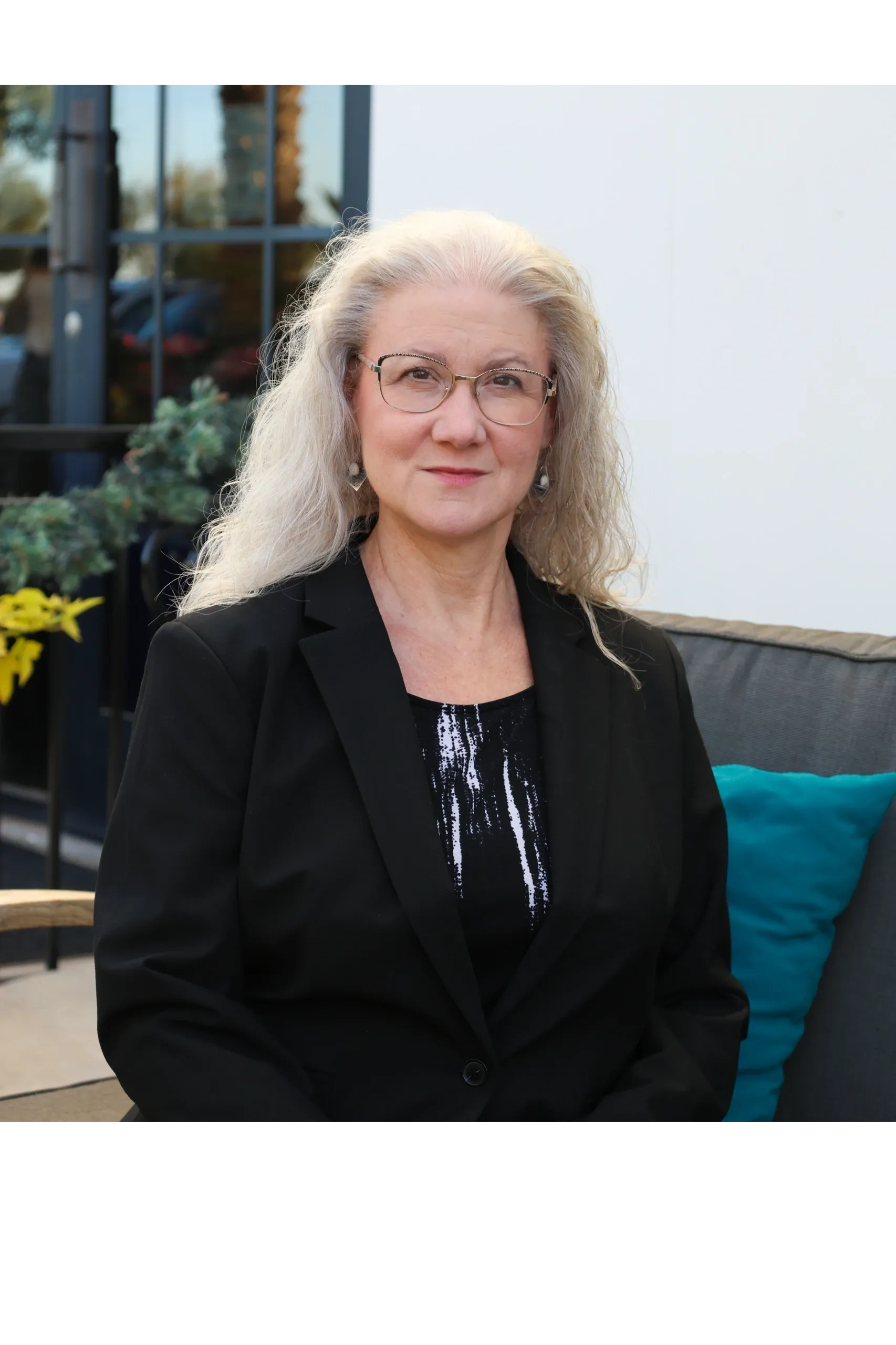 Dalena Watson, counselor and therapist, in a black suit, sitting on a couch outdoors.