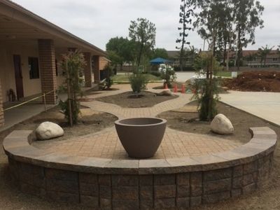 Curved stone patio with planter and rocks.