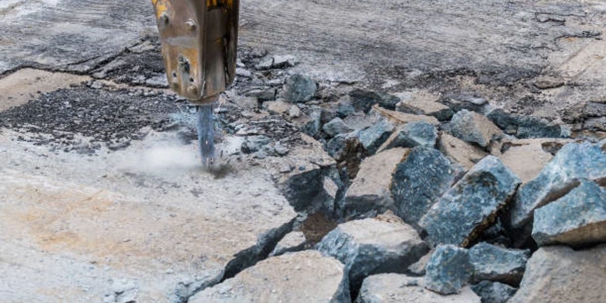 Machine breaking concrete pavement with a jackhammer.