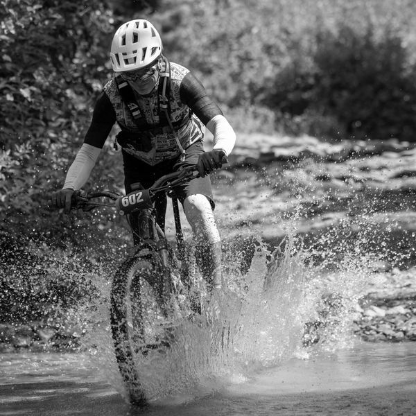 Cyclist splashing through water on a mountain bike.
