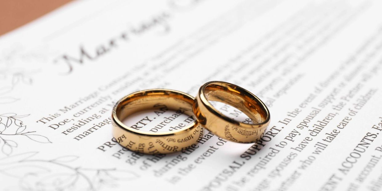 Two gold wedding rings on a marriage certificate.