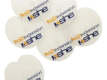 Round white hair extension labels with "b she" branding.