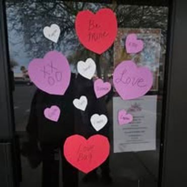 Colorful heart-shaped notes with love messages on a glass door.