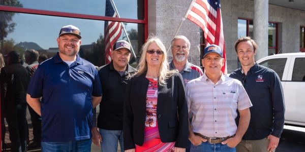Group of six people outside a building with American flags.