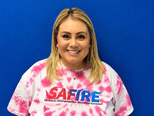 Smiling woman wearing a tie-dye SAFIRE t-shirt against a blue background.
