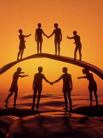 Silhouettes of people holding hands under a warm orange sky, symbolizing unity.