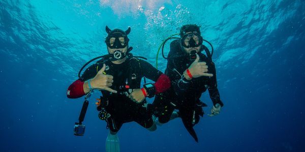 Two scuba divers during scuba training underwater showing the shaka hand sign.