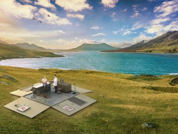 An outdoor office setup by a lake with two people working.