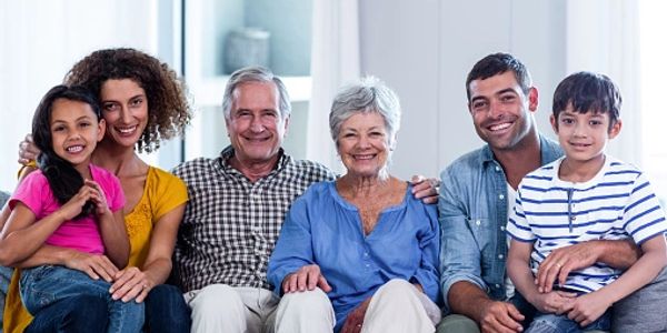 Smiling multigenerational family sitting together on a couch indoors.
