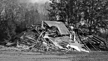 A pile of wooden debris and rubble in a forested area.