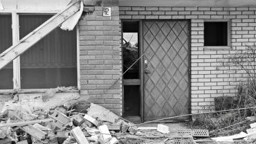 Damaged building entrance with debris scattered outside.