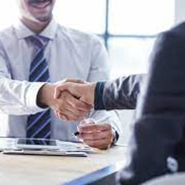 Two professionals shaking hands across a desk.