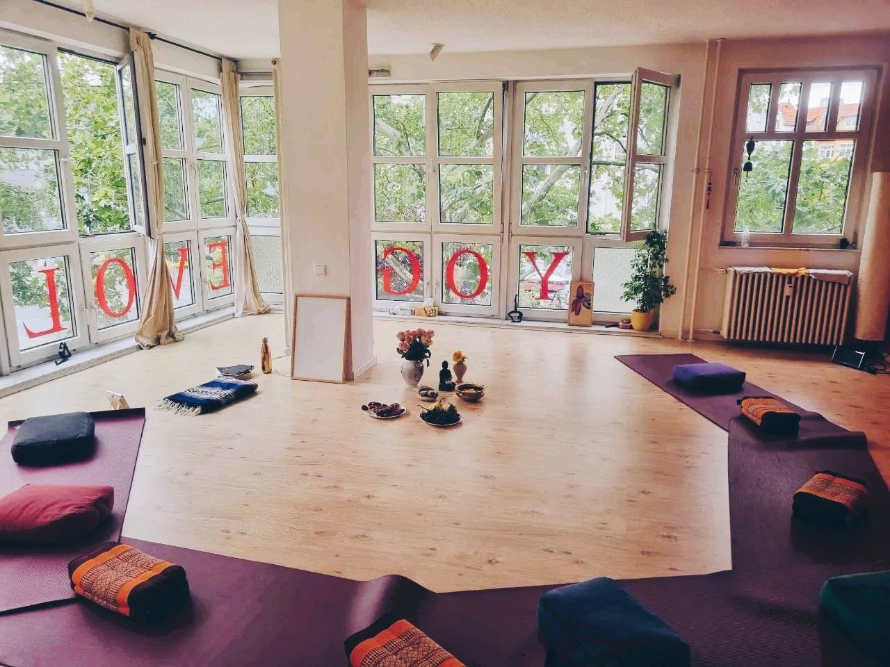 A calm yoga studio with mats and meditation pillows arranged in a circle.