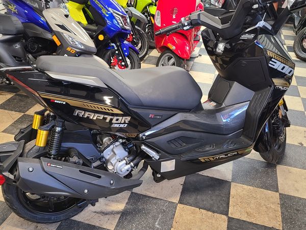 Black Raptor 300 scooter parked on checkered floor inside showroom.