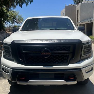 Front view of a white Nissan Titan truck under bright sunlight.