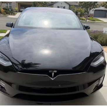 Black Tesla car parked in driveway.