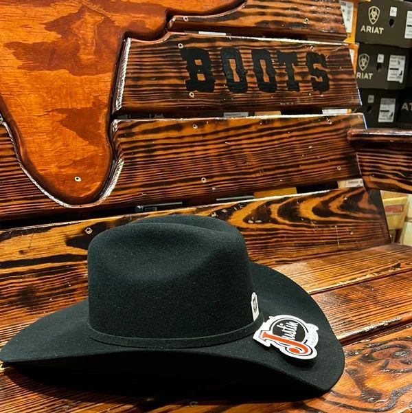 Black cowboy hat on a wooden bench labeled 'BOOTS'.