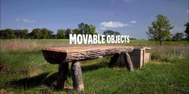 Rustic wooden bench and box in a grassy field under a blue sky.