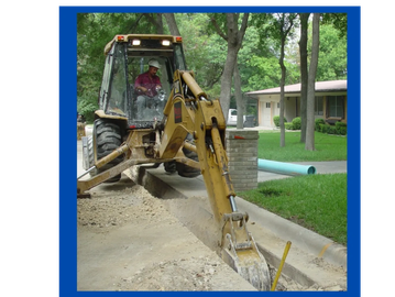 Excavator digging a trench near a residential area.