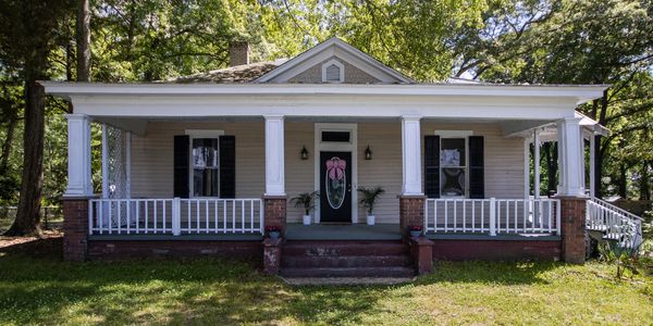 Cozy house with front porch, white pillars, and a decorated door.