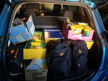 Car trunk filled with school supplies and backpacks.
