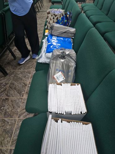 Boxes and packages on green chairs with a person nearby.