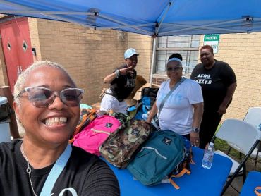 Group of four people smiling under a canopy with backpacks.