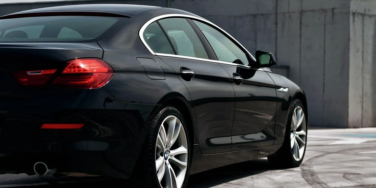 Sleek black BMW sedan parked near a concrete wall.