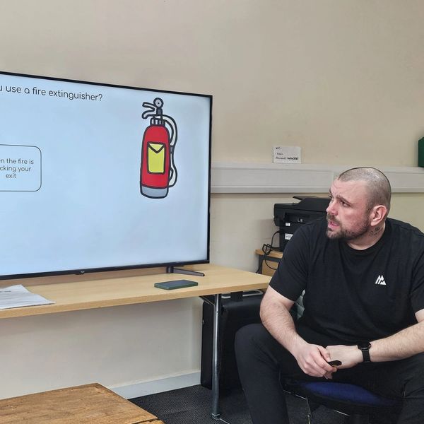 Man attentively watching fire extinguisher safety instructions on a screen.