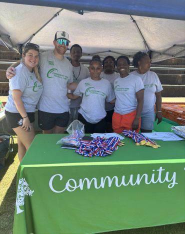 Group posing behind a Community event table with medals.