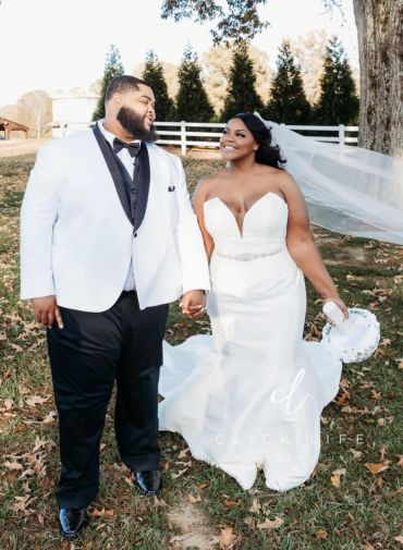 Smiling bride and groom holding hands outdoors on their wedding day.