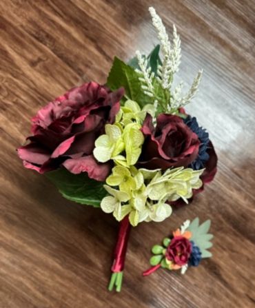 Elegant bouquet with dark red roses and light green flowers on wooden floor.