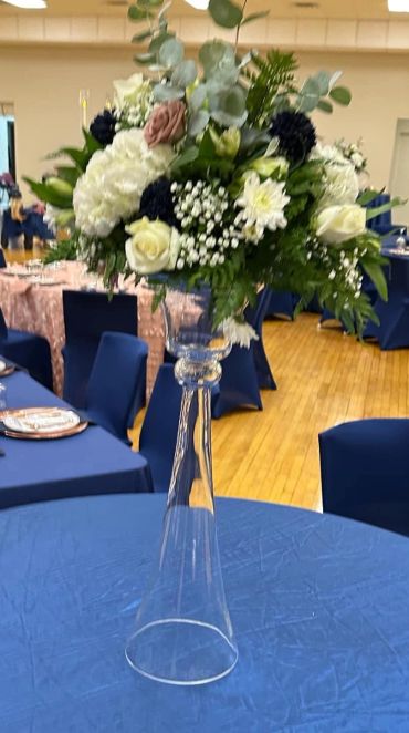 Elegant floral centerpiece on a tall clear vase at an event.