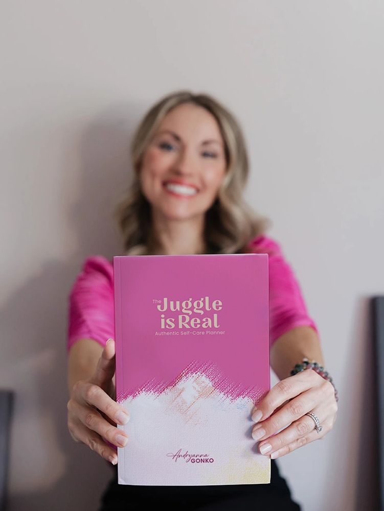 photo of Andryanna holding out a copy of The Juggle is Real Authentic Self-Care Planner